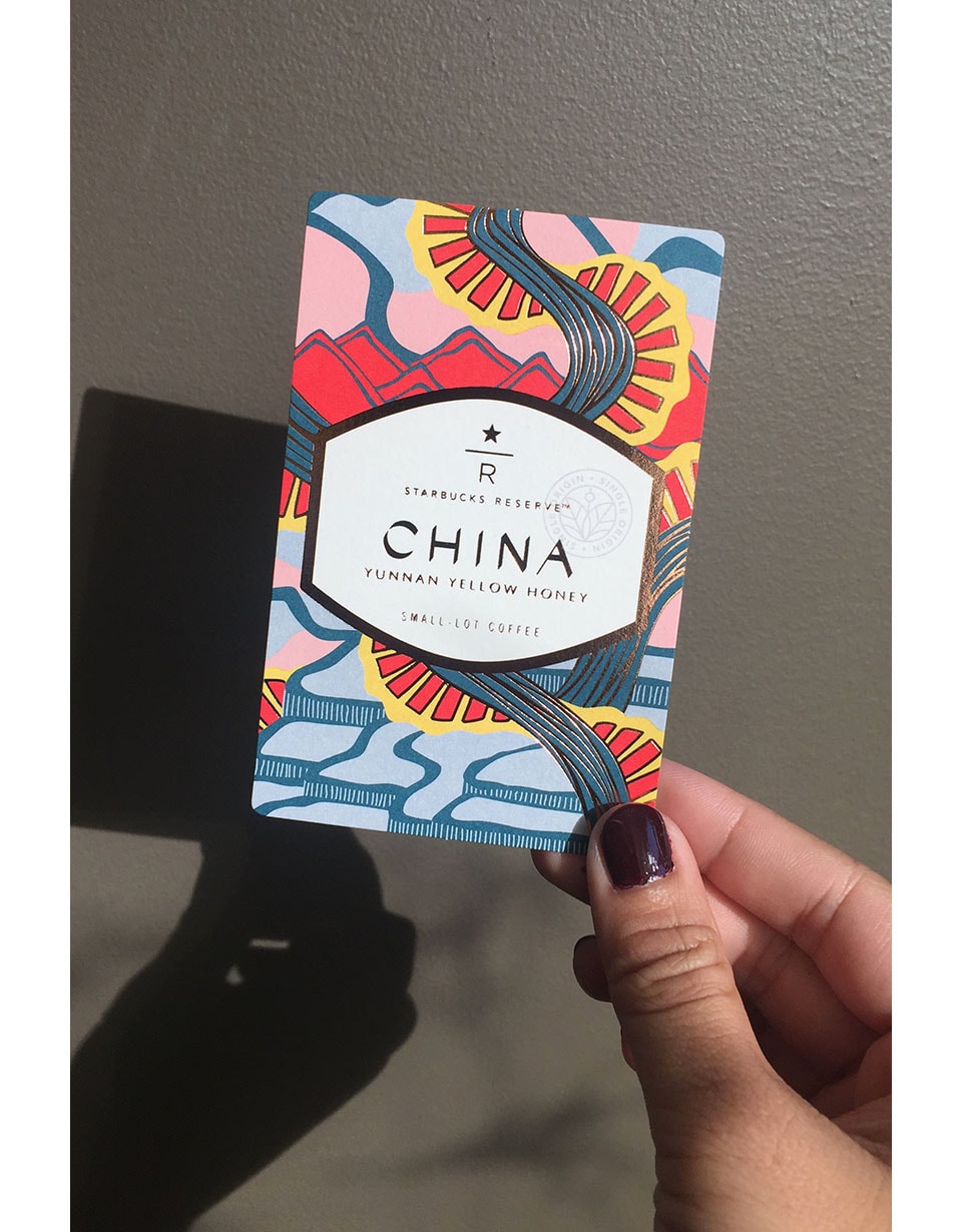 Hand holding a coffee card that reads "China" in front of a wall