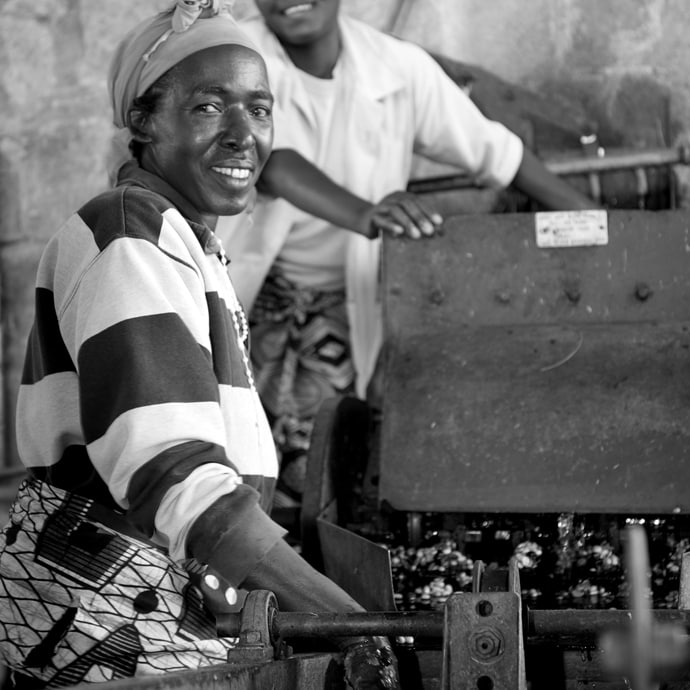 Black and white image of woman operating machinery and smiling at the camera