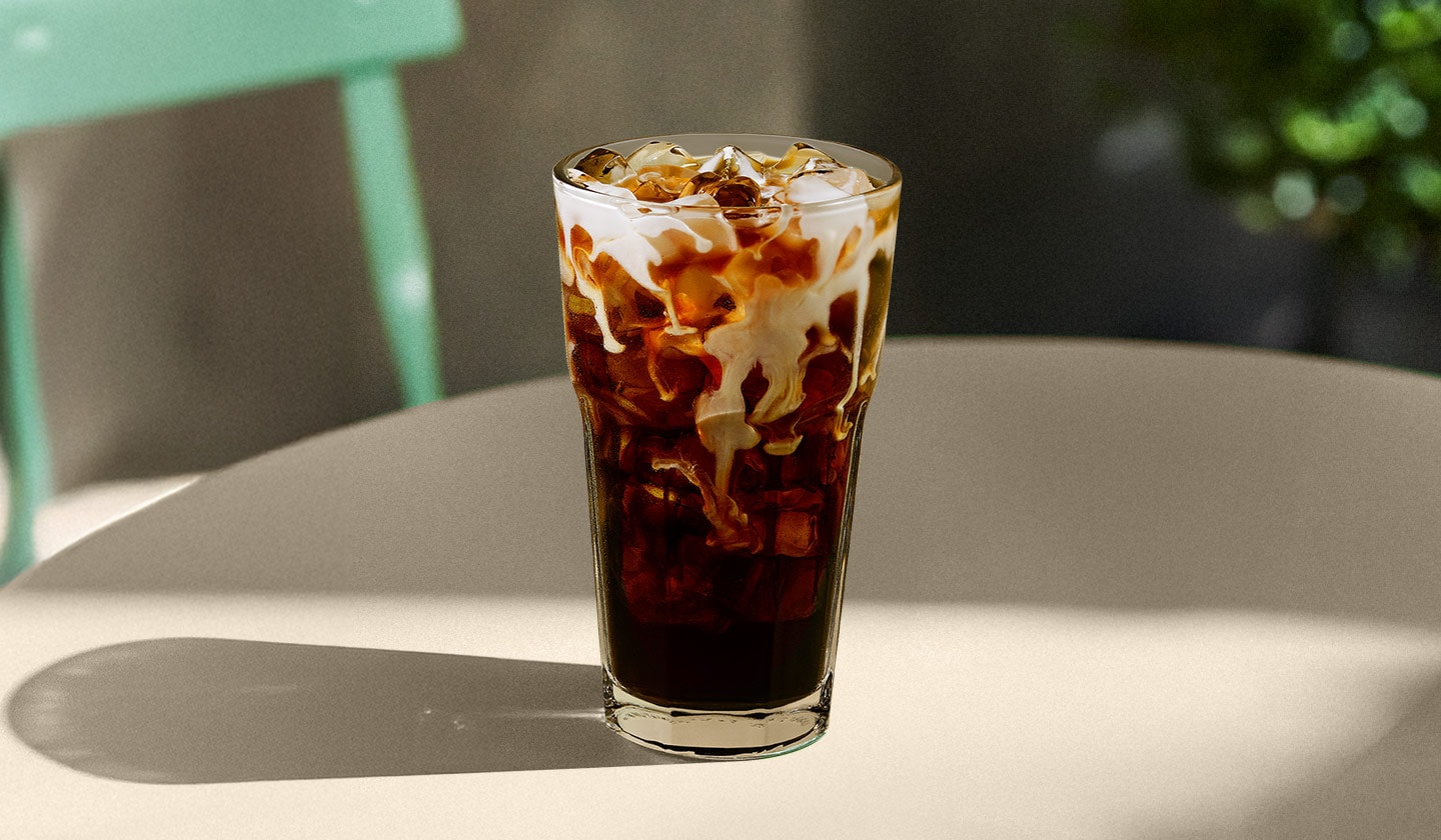 A vanilla Sweet Cream Cold Brew sitting on a table outside on a patio.