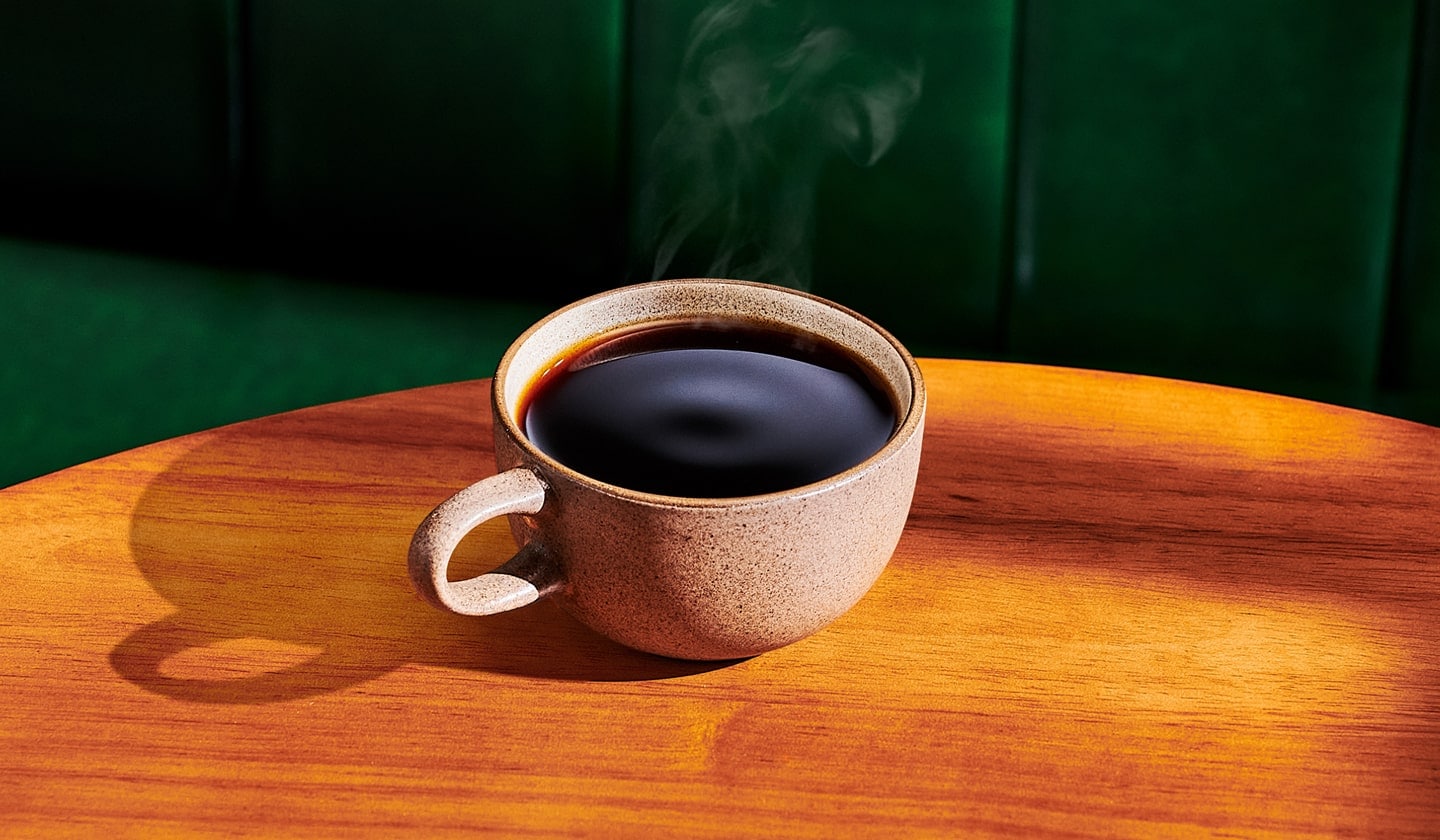 A mug of hot coffee on a wooden table.