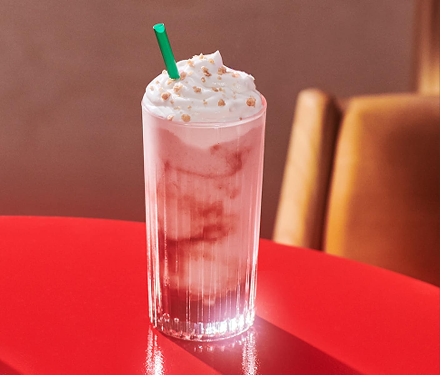A Strawberry Shortcake Frappuccino® blended beverage sits on a red table.