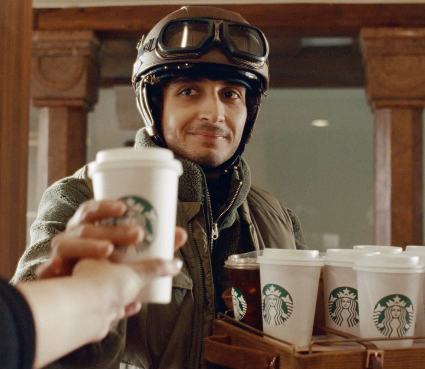 A man holding a full drink carrier hands off a Starbucks drink