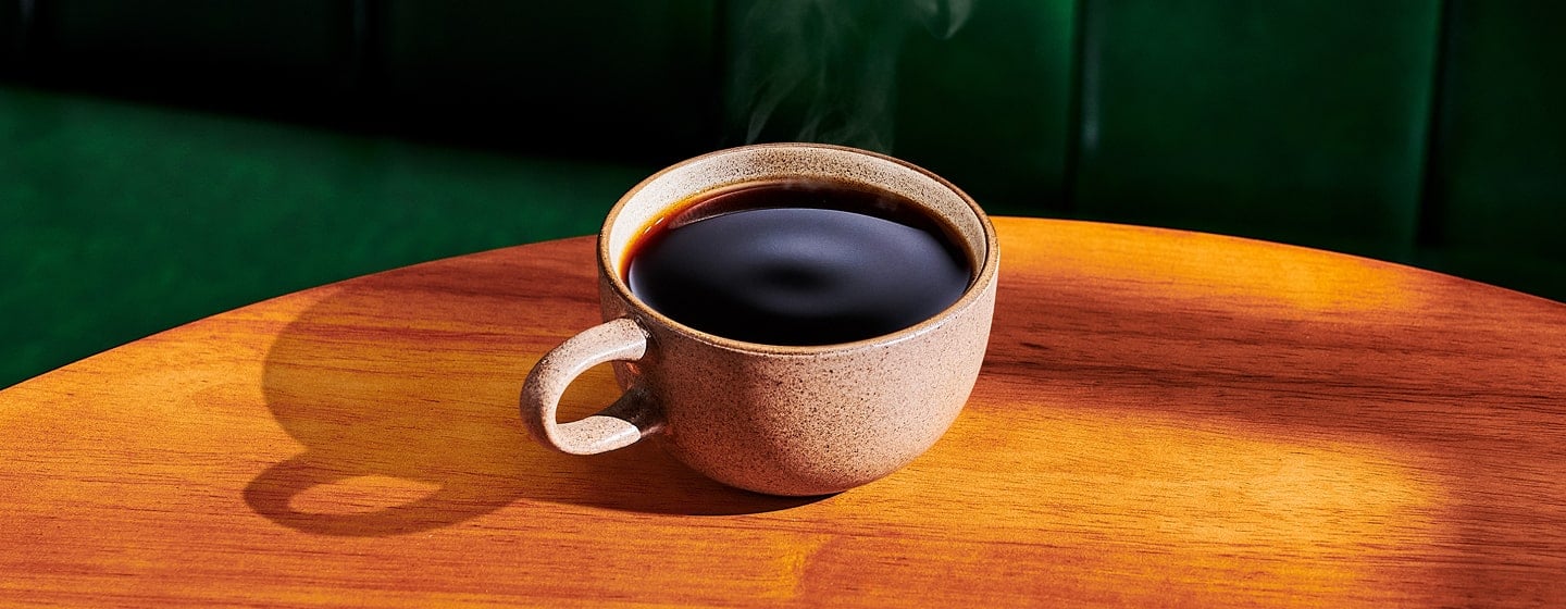 A mug of hot coffee on a wooden table.