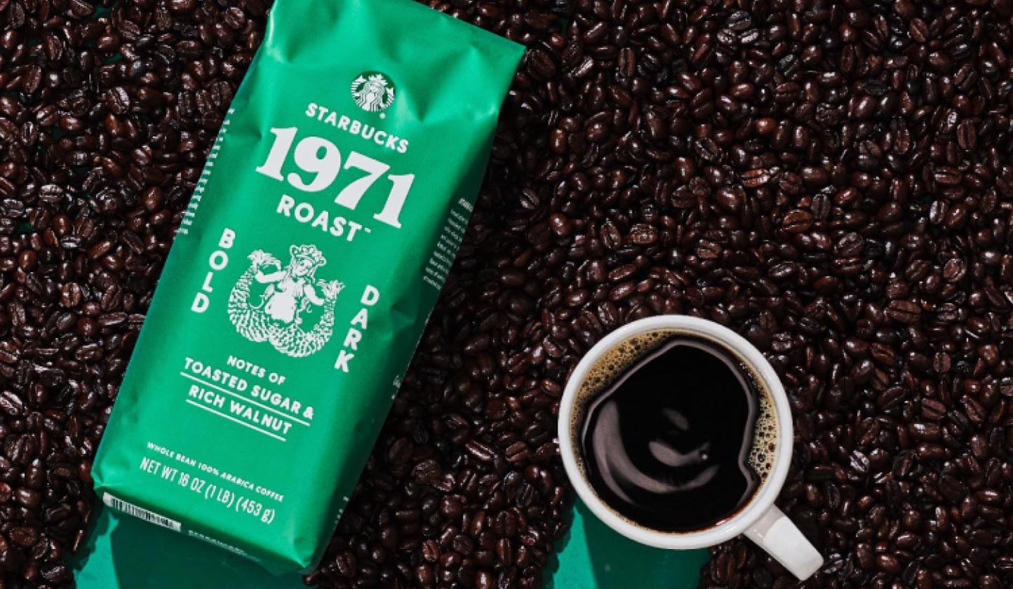 Top‑down view of a mug of Starbucks 1971 Roast™ coffee resting on a bed of coffee beans.