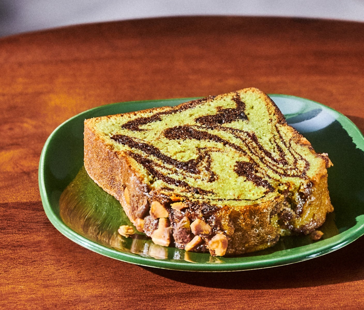 A slice of bread with chocolate swirls and topped with nuts on a plate.