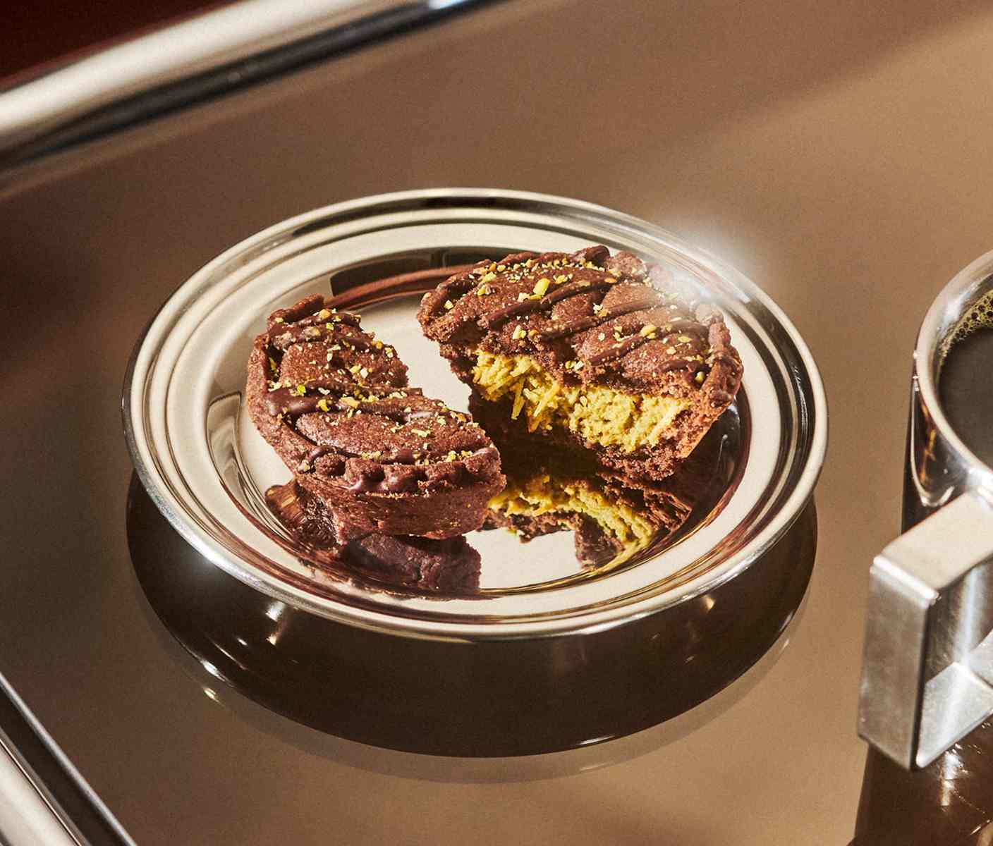 A plate containing two halves of a round baked tart with a cream filling and nutty, drizzly toppings.