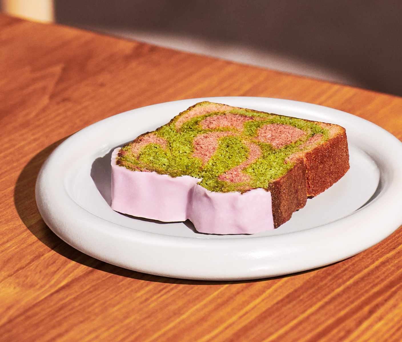 A slice of marbled cake with icing on a plate.