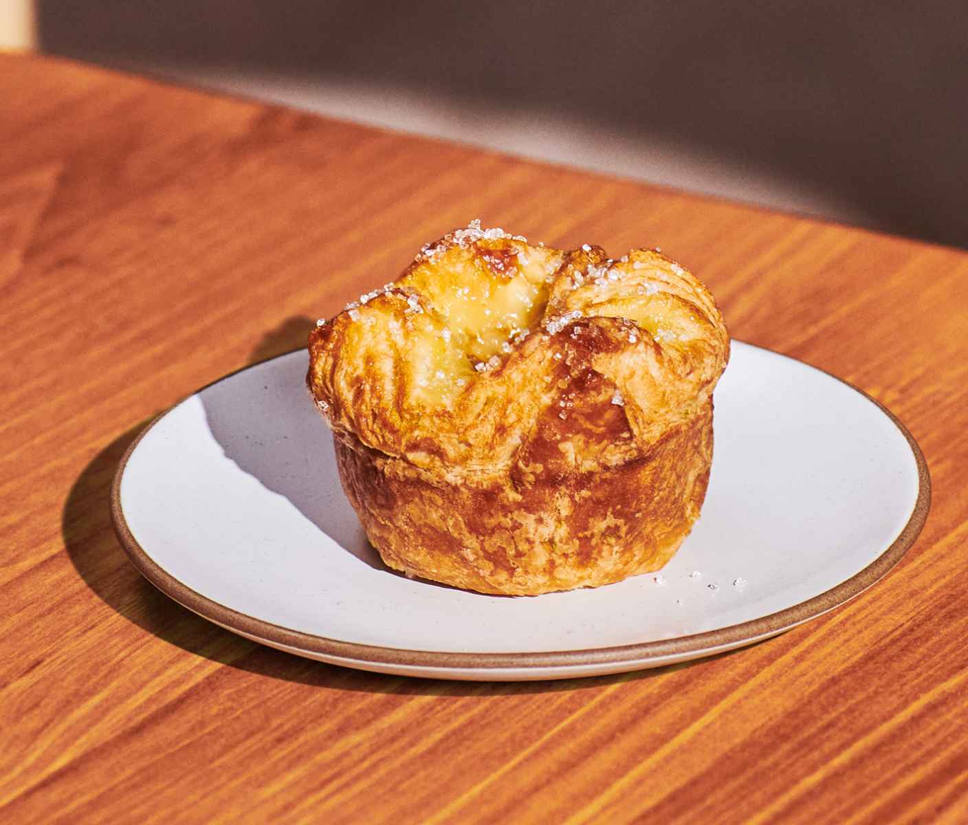 A flaky upright pastry with sprinkles on top on a plate.