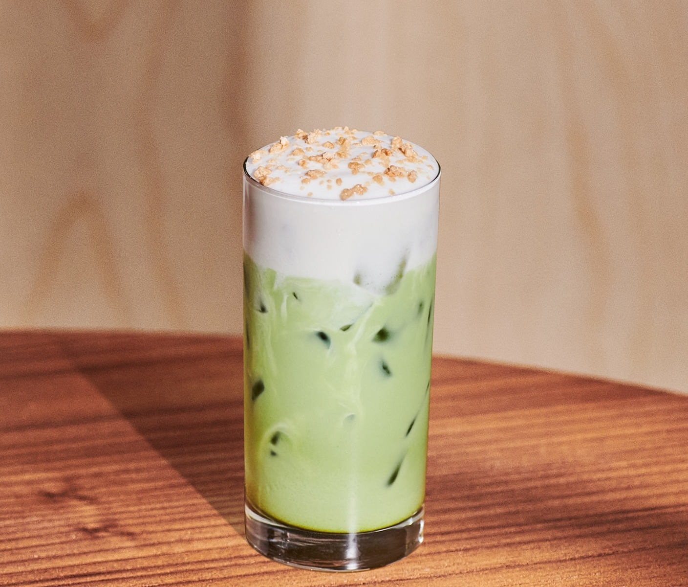 An iced creamy tea drink in a glass with a thick foamy top and sprinkles.