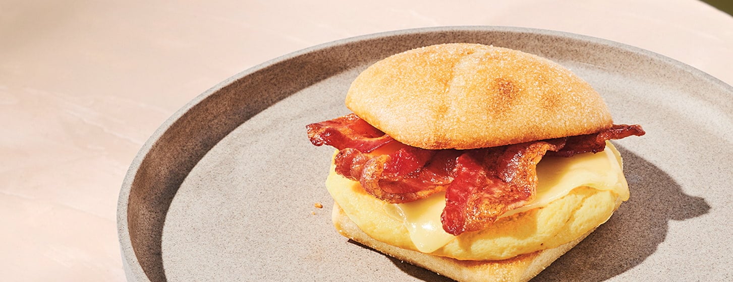 Bacon, melted cheese and eggs stacked inside a toasted bun.
