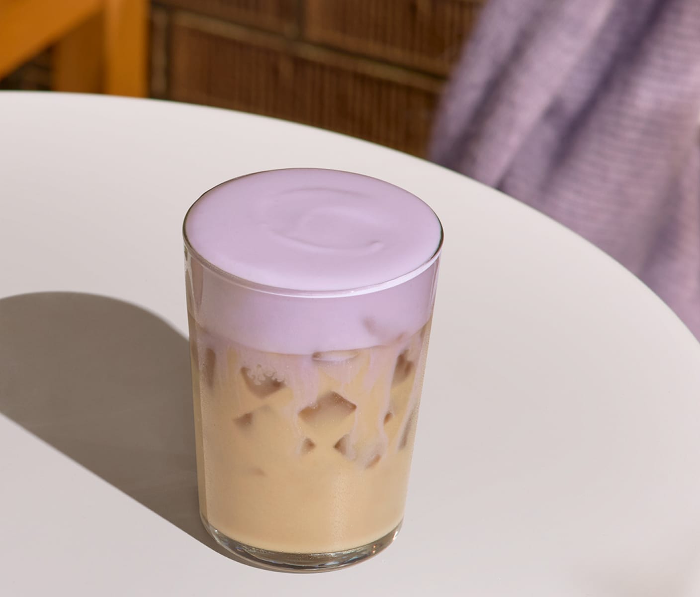 A creamy iced tea drink with a thick foamy top in a glass.
