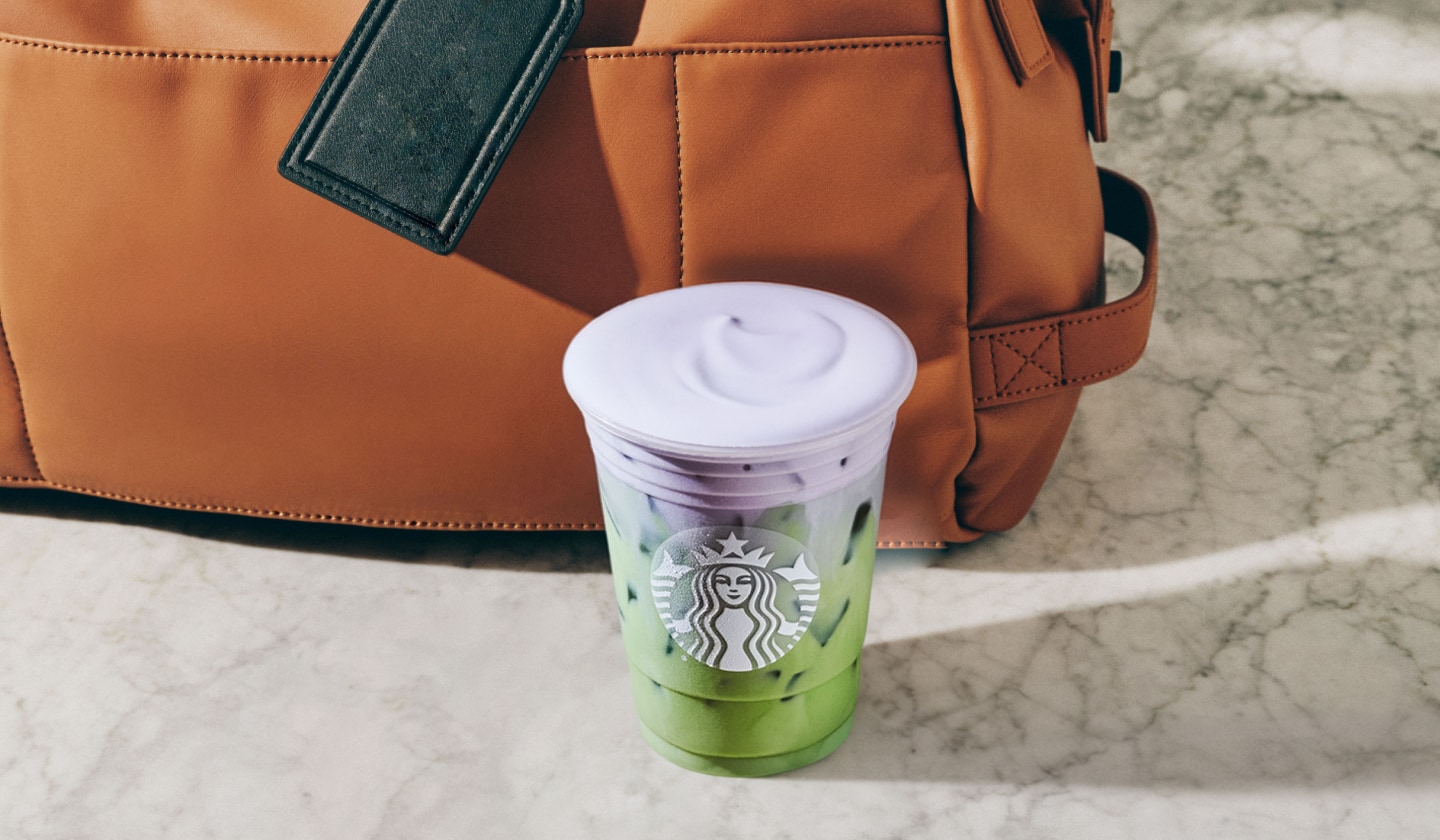 A creamy iced tea drink with a thick foamy top in a clear cup.