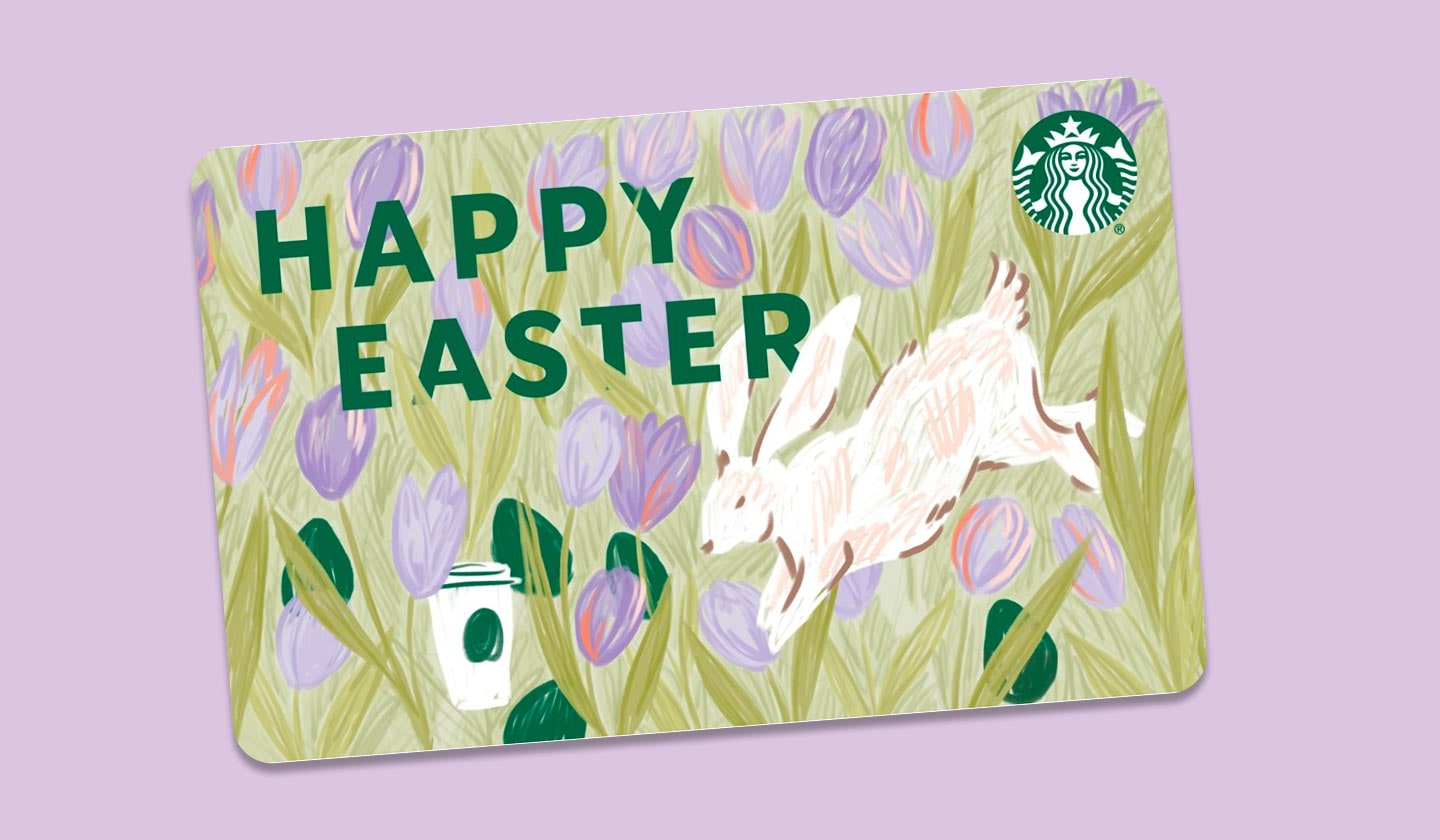 On a lavender background, a Starbucks gift card with an illustration of a white rabbit and a Starbucks drink in a field of purple tulips reads "Happy Easter."