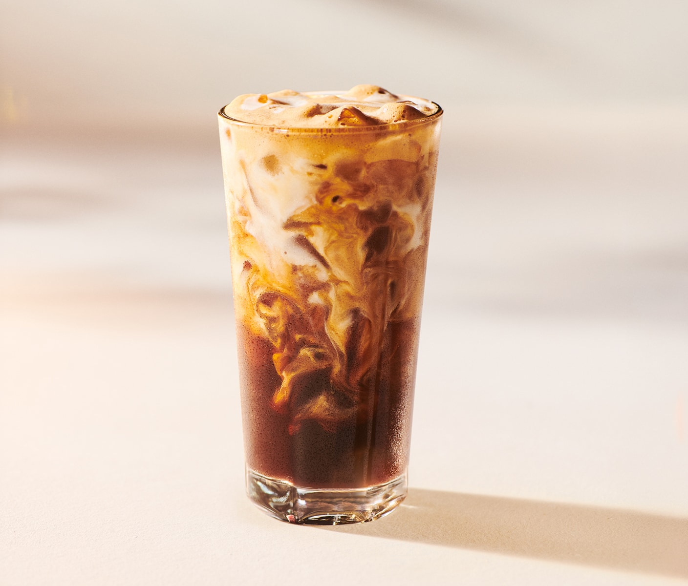 An iced coffee drink with cascading milk in a glass.