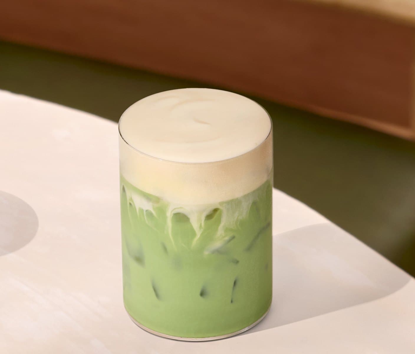 A creamy iced tea drink with a thick foam topping in a glass.