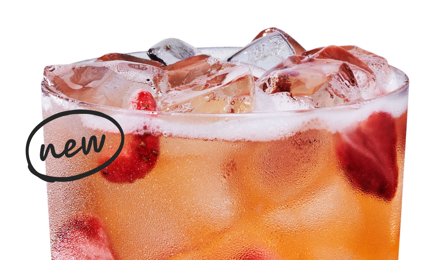 Close up of an iced mango and strawberry flavored drink with strawberry pieces in a glass.