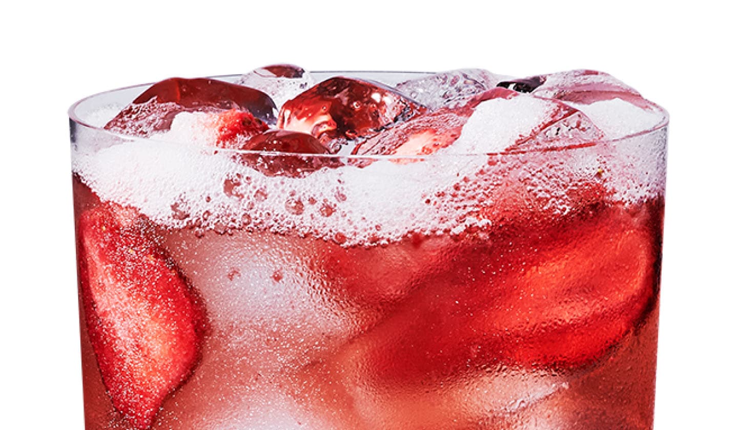 Close up of an iced açaí and strawberry flavored drink with strawberry pieces in a glass.
