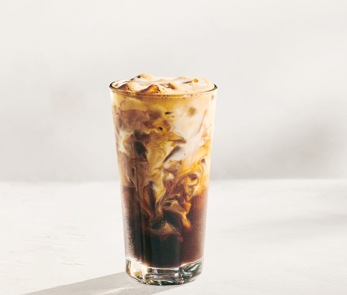 An iced coffee drink in a glass with creamy marbling.