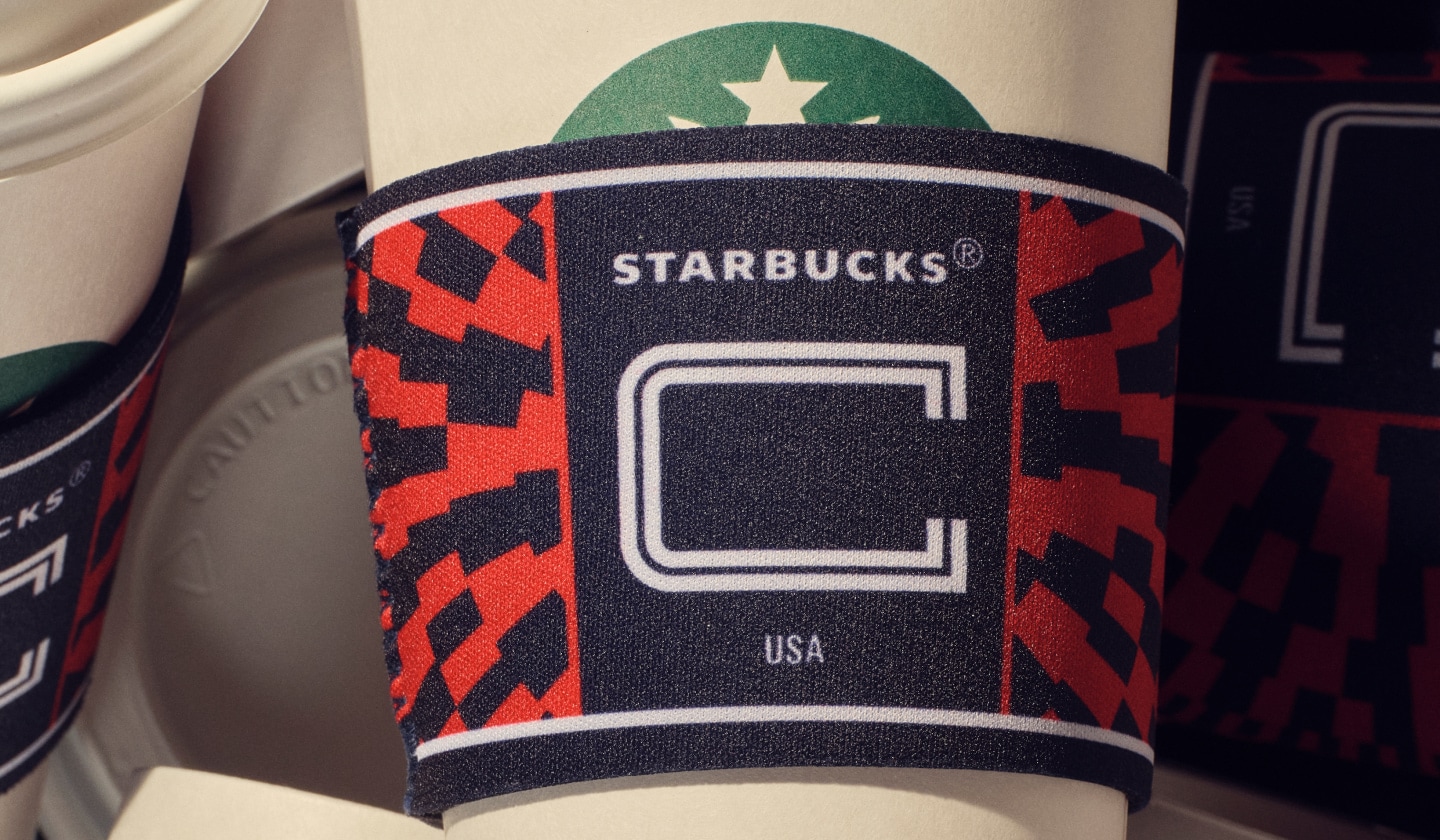 A limited-edition cup sleeve that mimics a soccer captain armband wraps around a Starbucks hot cup
