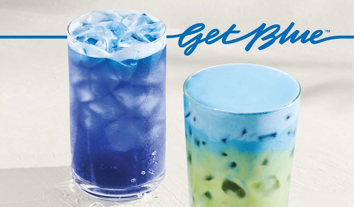 An iced blue drink next to an iced matcha with light-blue cold foam on a light-gray surface. Blue script that reads “Get Blue” sits above the drinks.