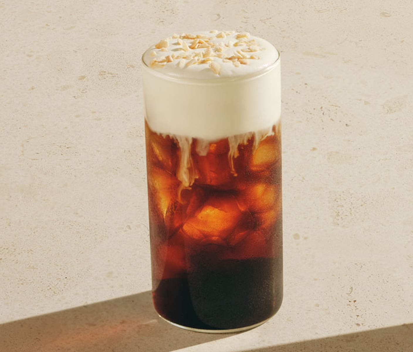 An iced coffee drink with a thick foamy top and sprinkles in a glass.