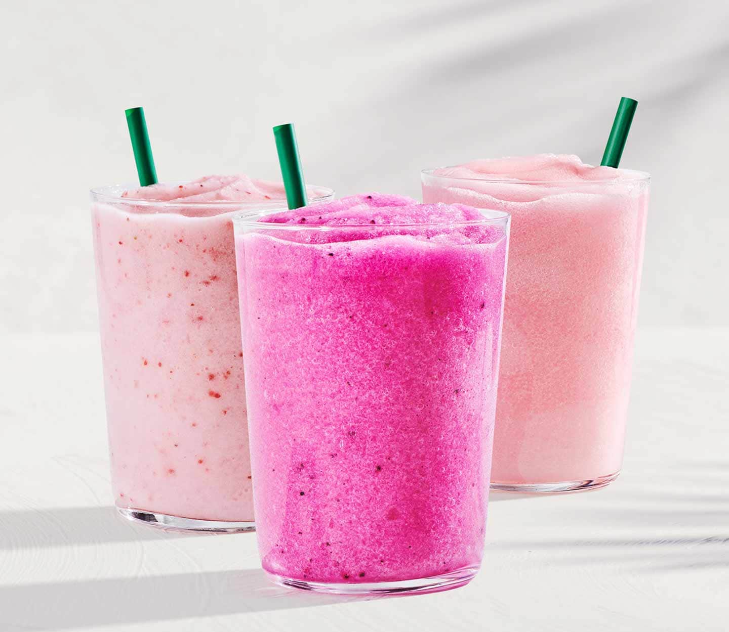 Three Blended Energy Refreshers in glasses with green straws on a white background.