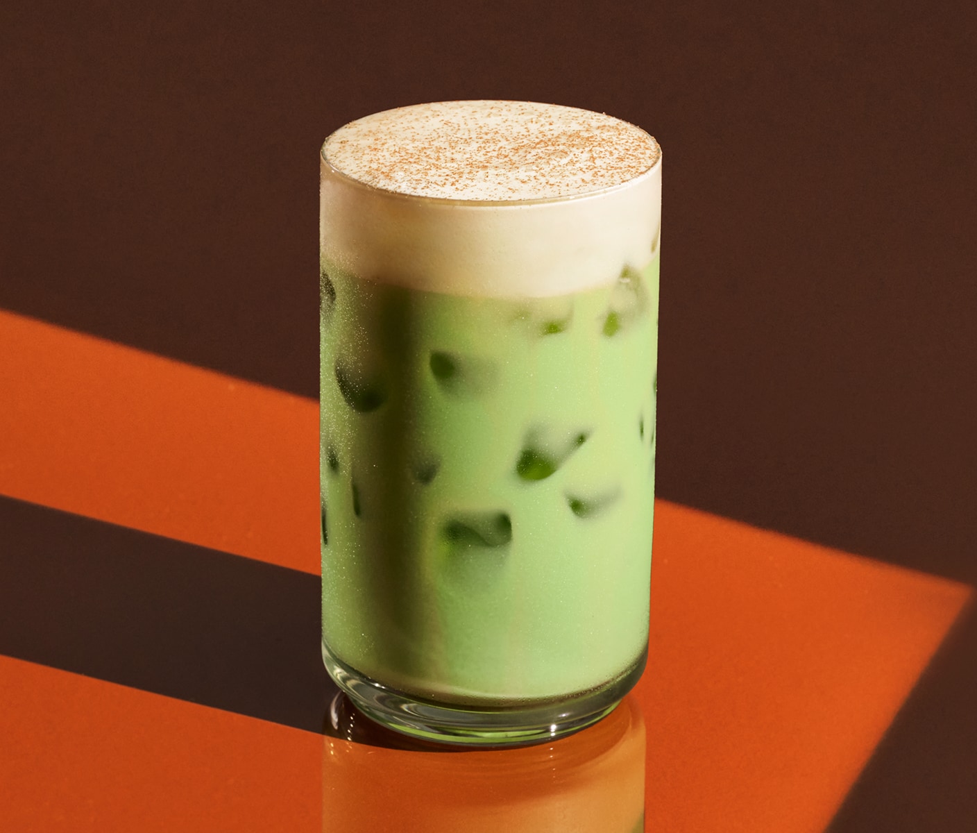 An iced matcha with pumpkin cream cold foam and spices.