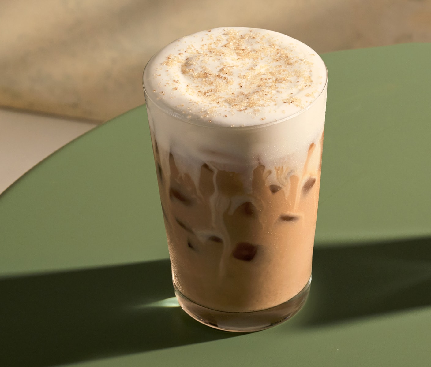 A milky iced coffee with vanilla sweet cream cold foam sprinkled with topping.