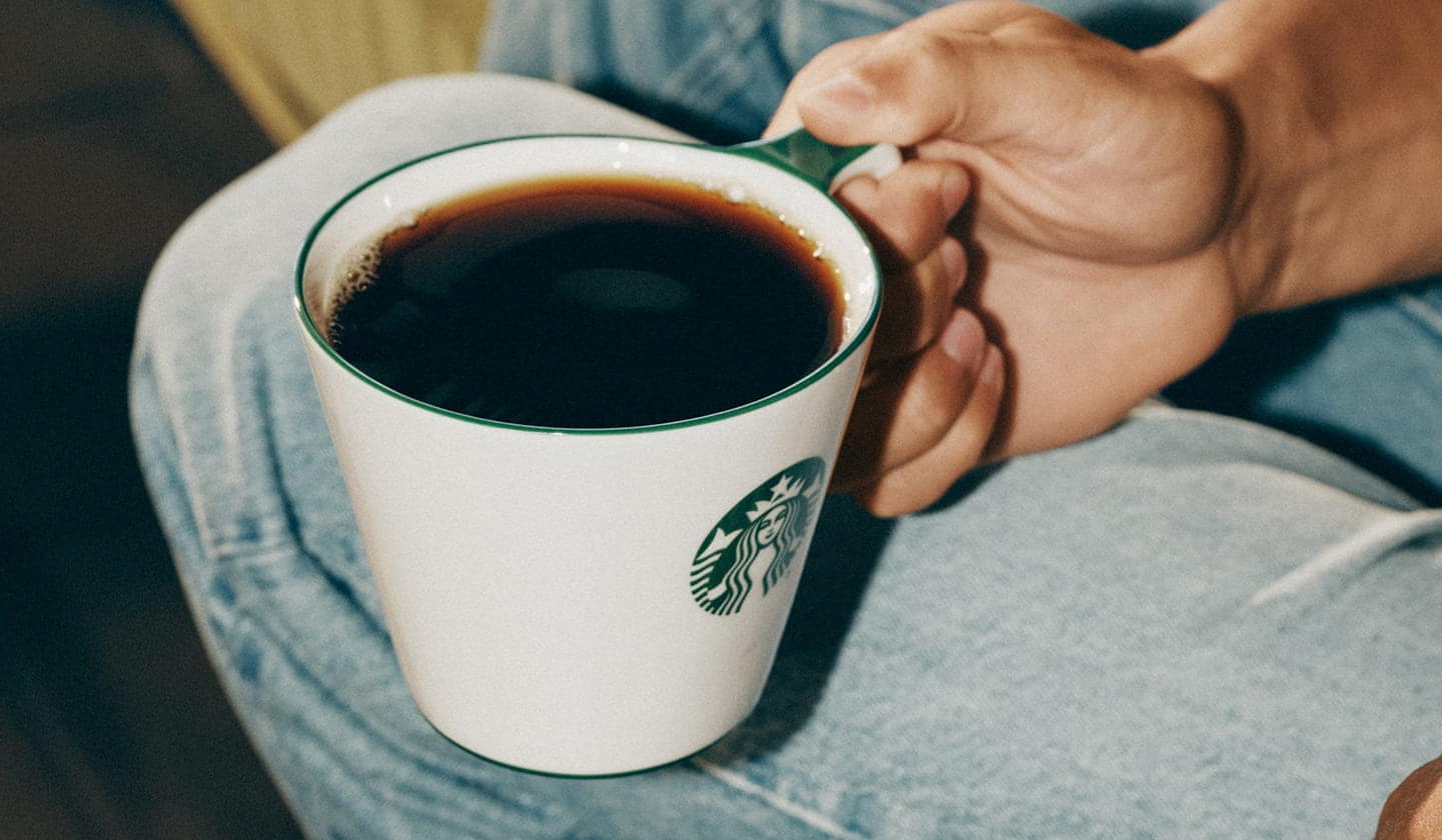 Close-up of someone holding a mug filled with coffee.