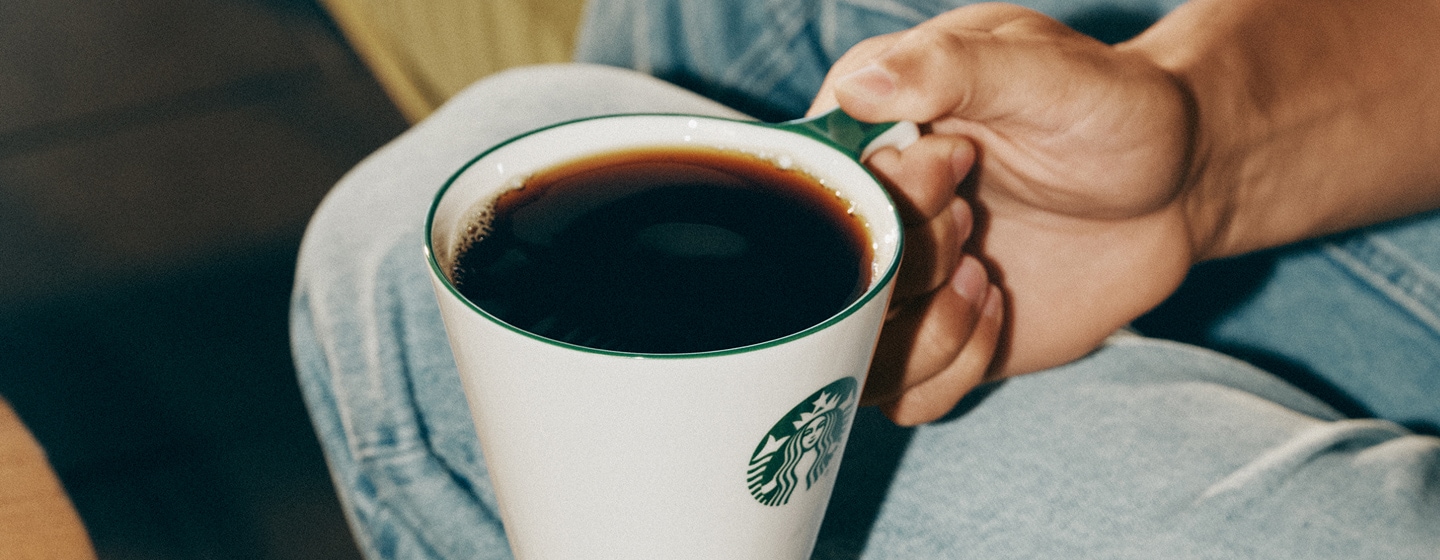 Close-up of someone holding a mug filled with coffee.