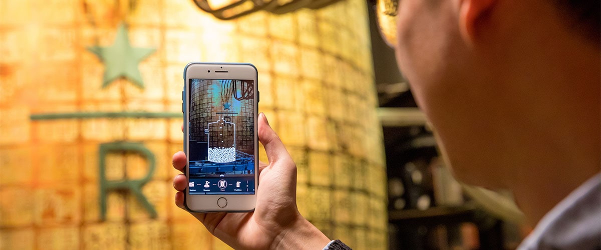 Customer holding smart phone displaying Starbucks Reserve mobile application