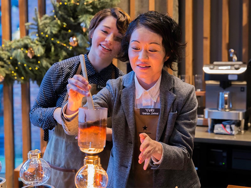 two employees at roastery brewing coffee