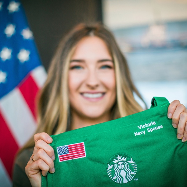 Female veteran holding up a green apron with embroidered American flag