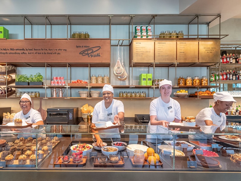 Four female Princi Bakery Partners smiling behind counter