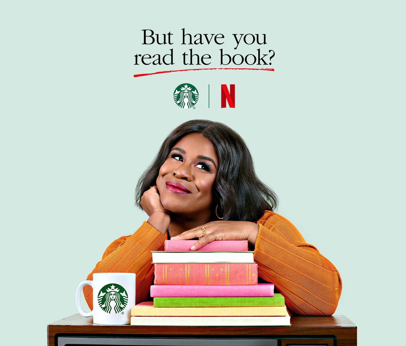 Actress Uzo Aduba poses with a pile of books, a TV and a Starbucks mug to promote a new series named But Have You Read the Book.