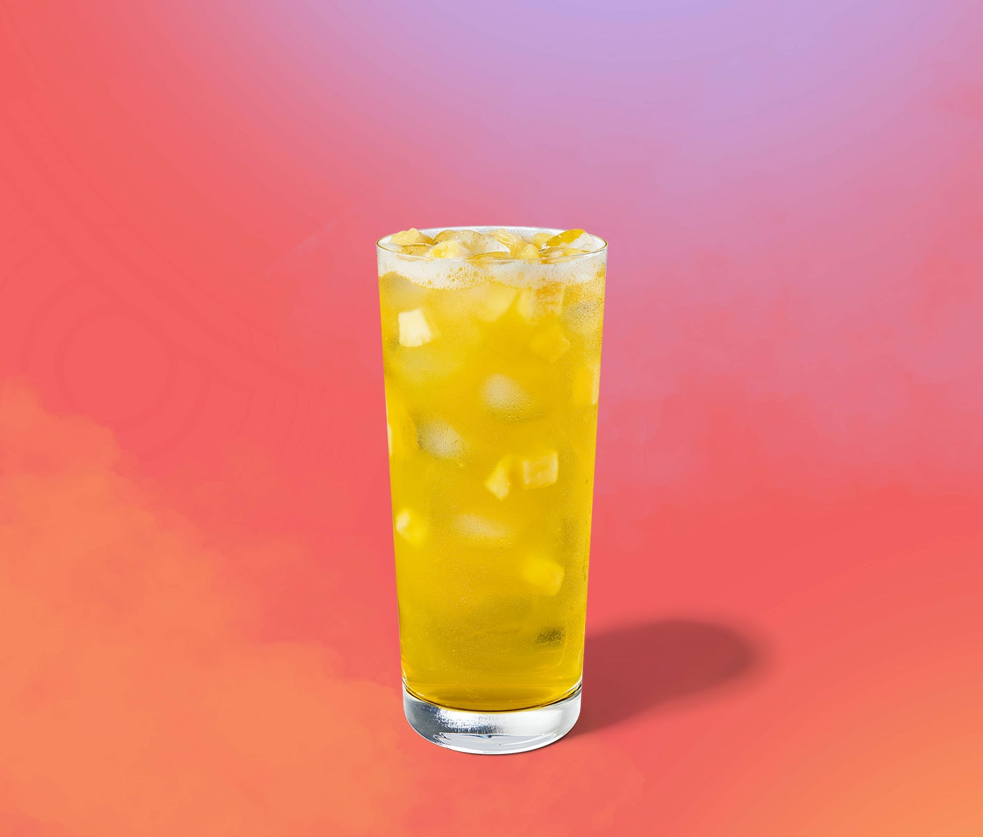 Bright-yellow iced drink with pineapple inclusions in a tall glass.