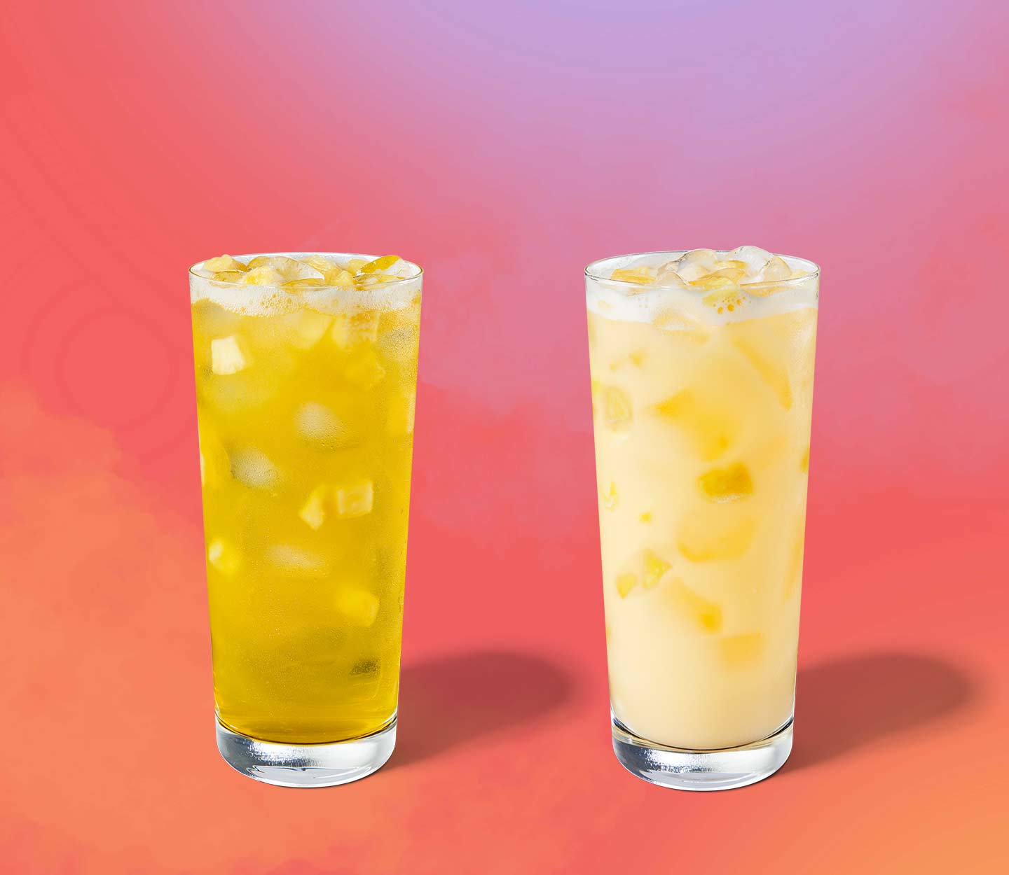 Two yellow iced drinks with pineapple inclusions in tall glasses.