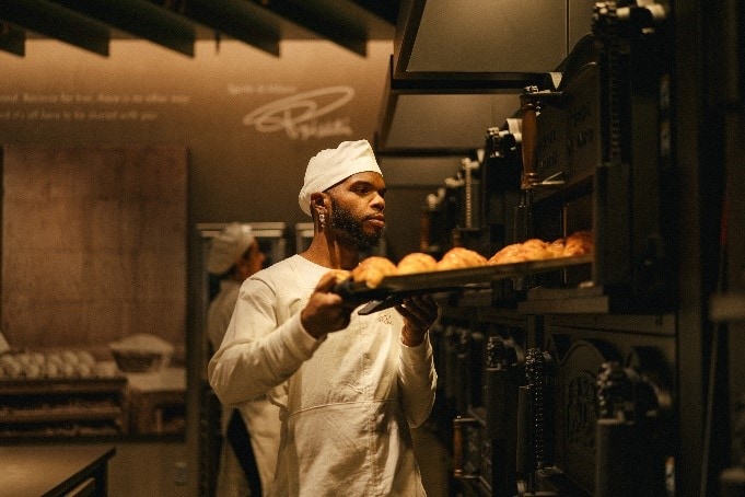 Starbucks partner (employee) loading bread into oven