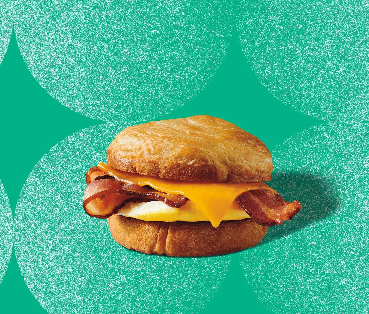 Bacon strips, melted cheese and a fried egg layered in a round croissant-style bun.