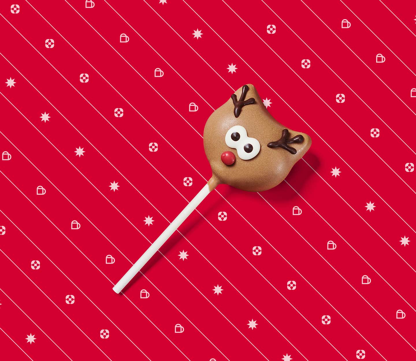 Cake pop decorated to look like a reindeer face with antlers, eyes and a red nose.