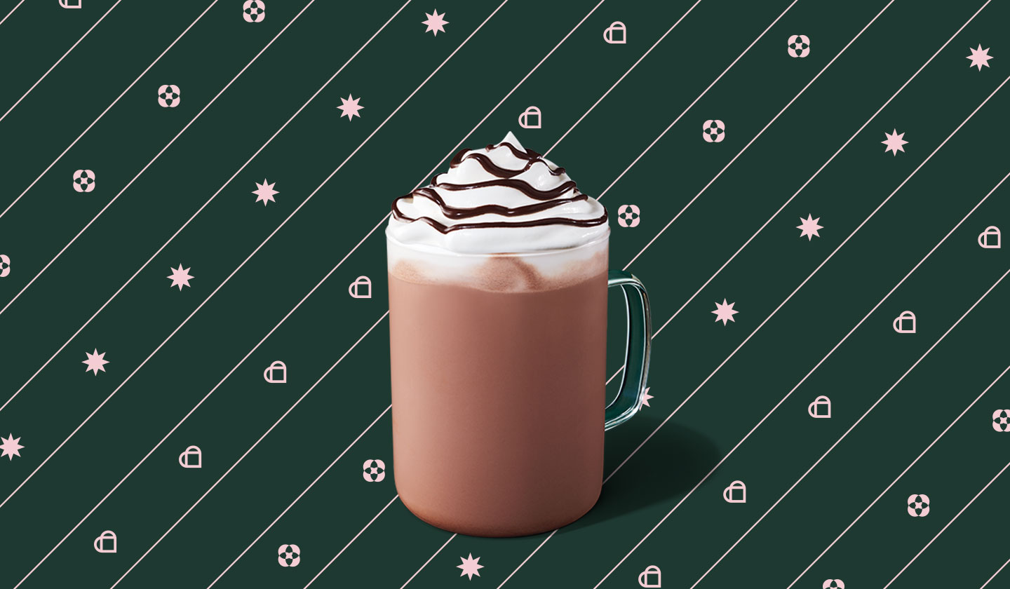 Hot chocolate with whipped cream and chocolate drizzle in a glass mug.