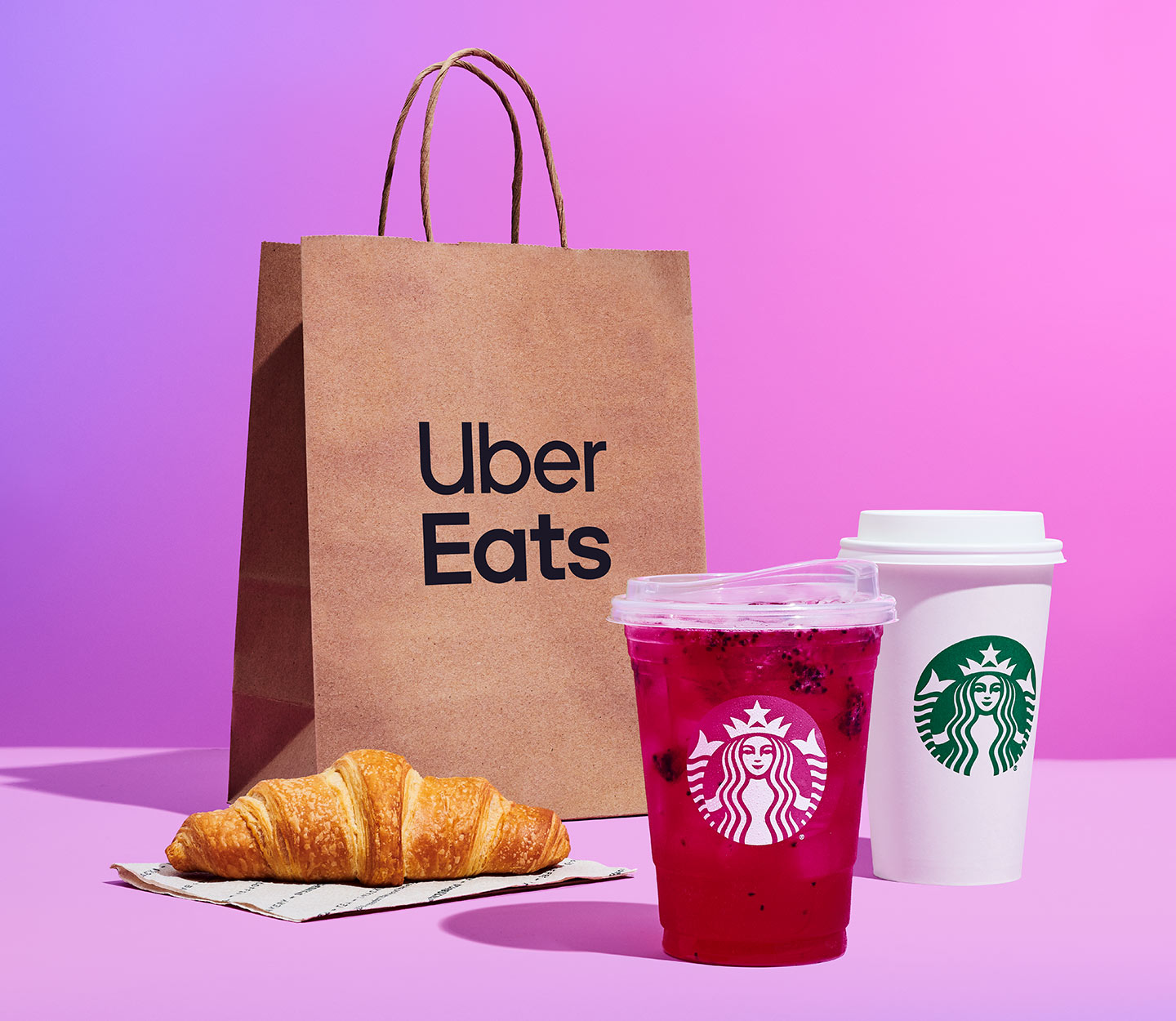 Uber Eats bag with two Starbucks drinks and a croissant.