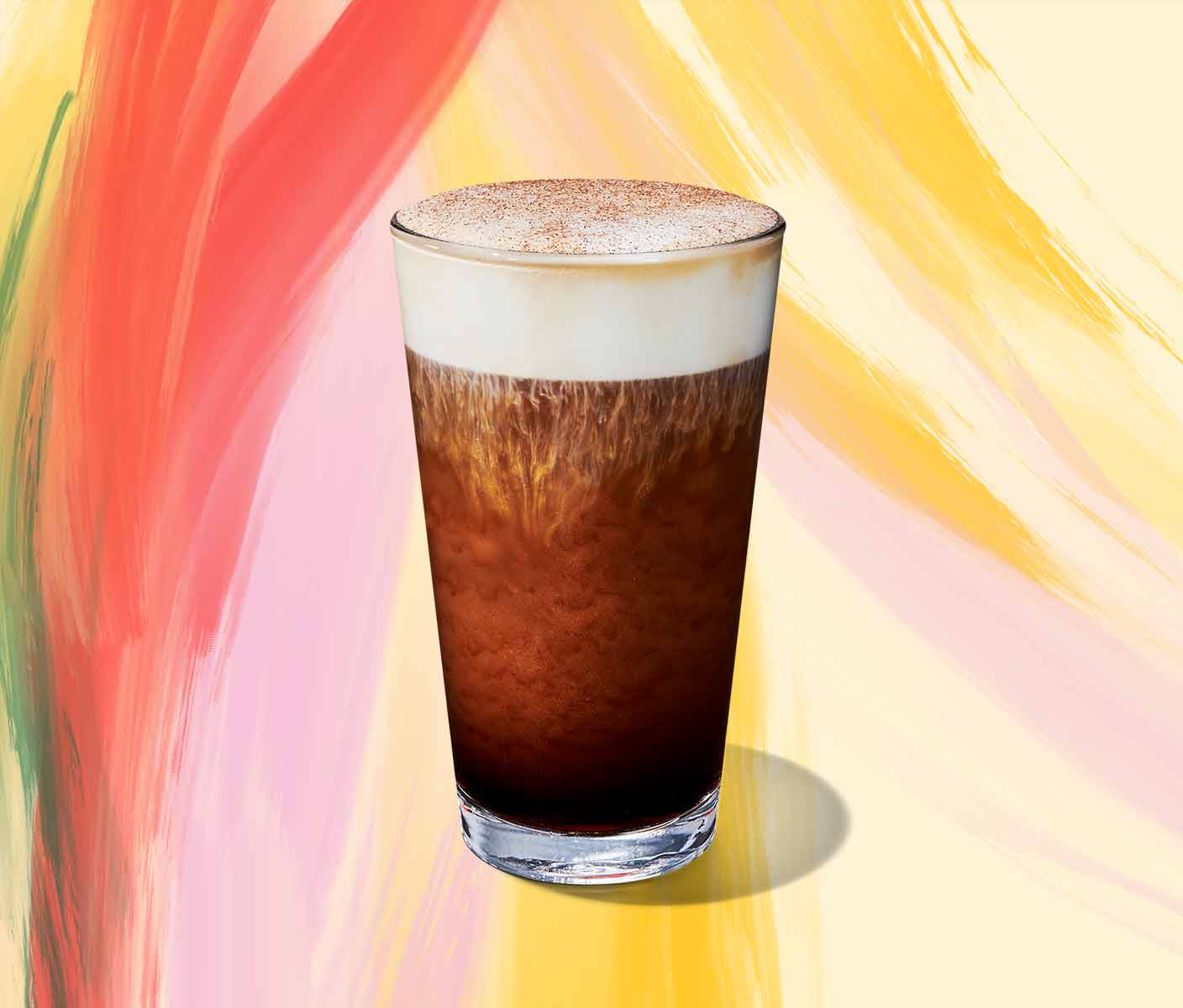 Cold coffee drink topped with foam in a tall glass.