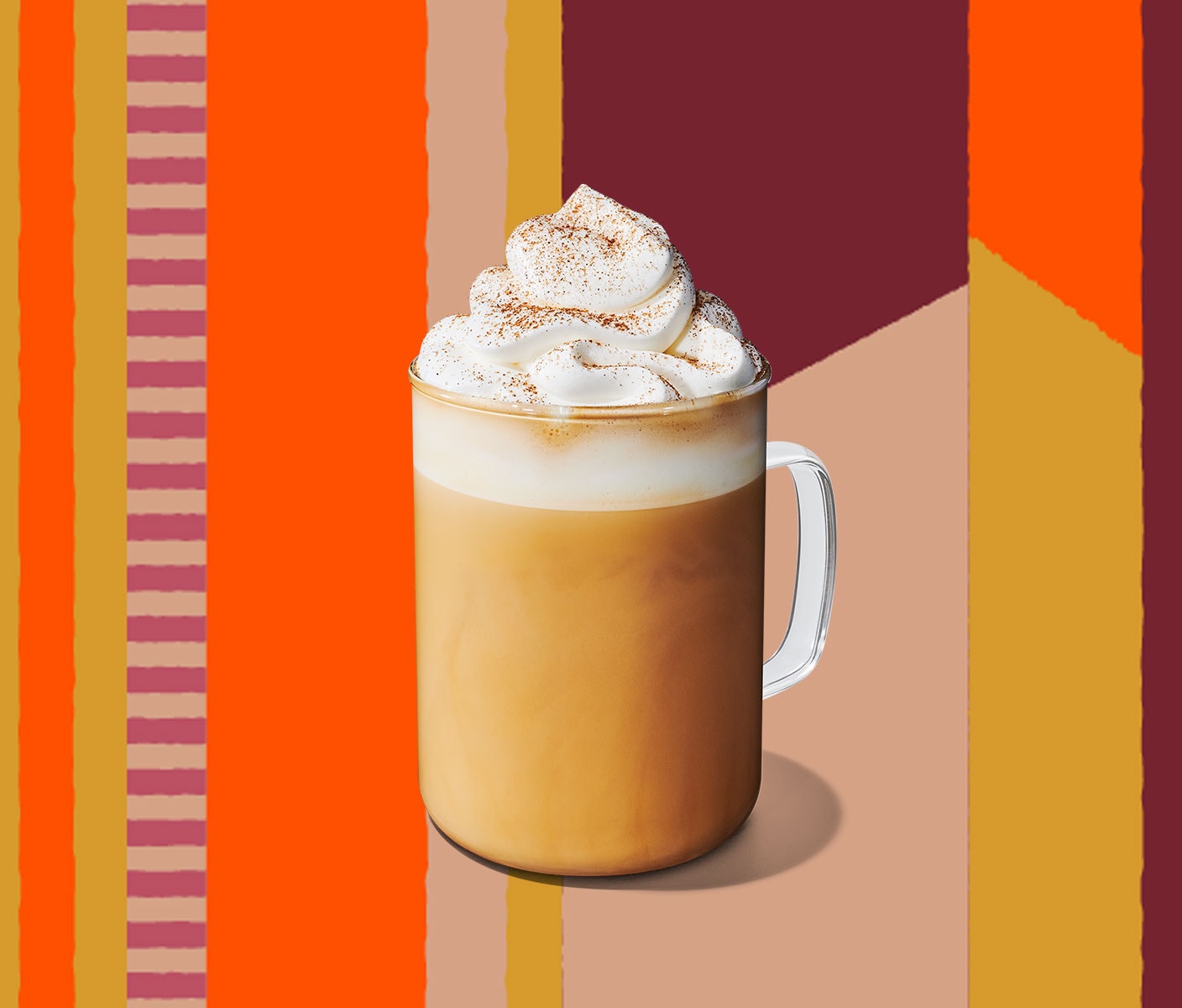 A creamy latte with whipped cream on top in a glass with a handle.