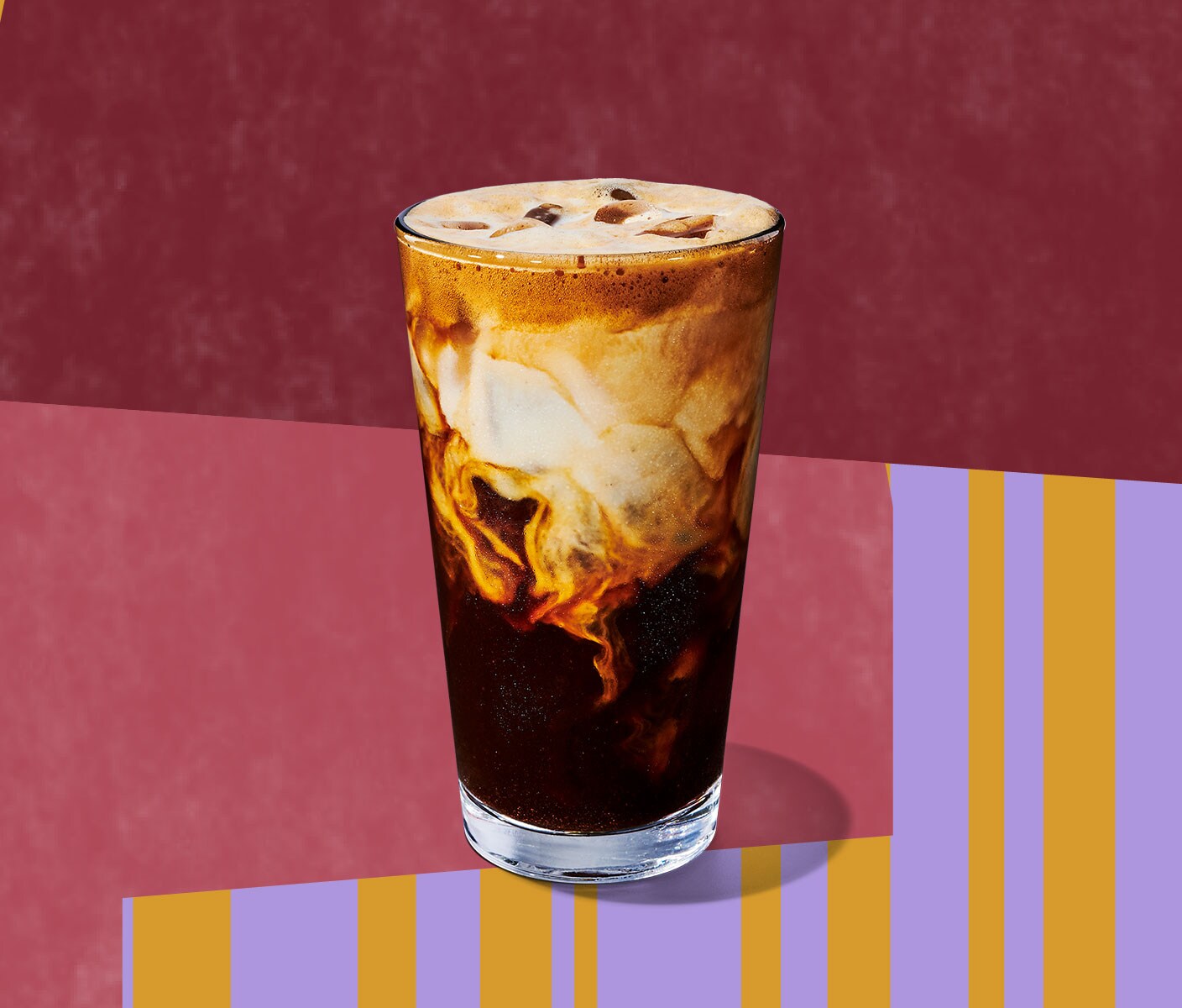 An espresso drink in a tall glass with a deep layer of creaminess on top.
