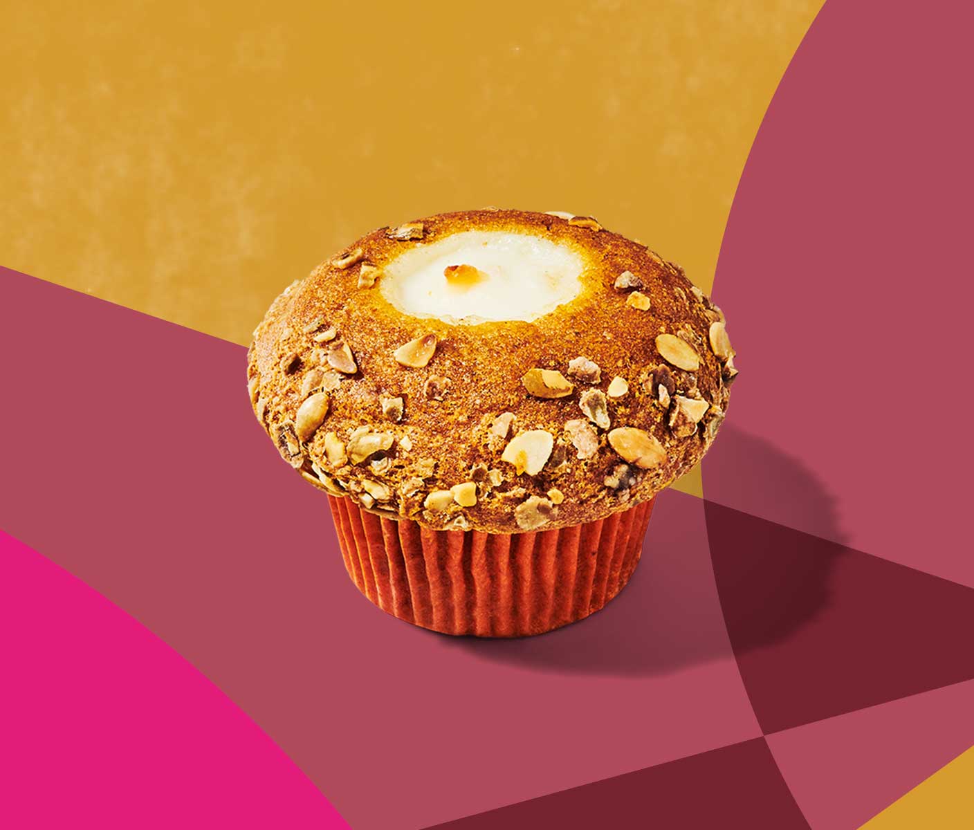 Overhead shot of a round muffin with a nutty topping and cream cheese showing through the top.