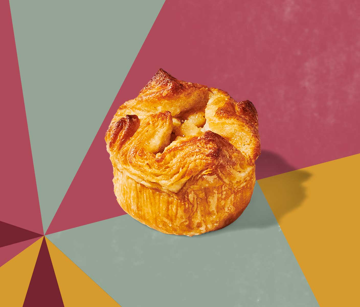 A round, flaky pastry with a wavy texture on top set against a geometric pattern.
