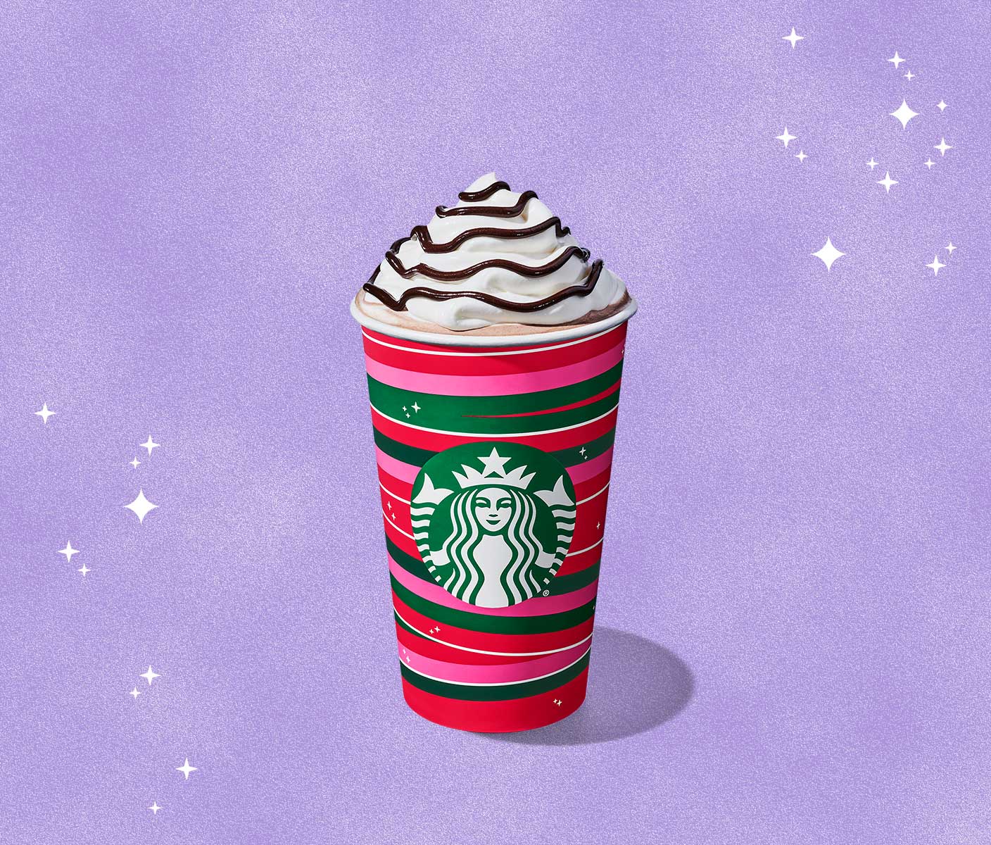 Hot chocolate with whipped cream and chocolate drizzle in a holiday-themed to-go cup.