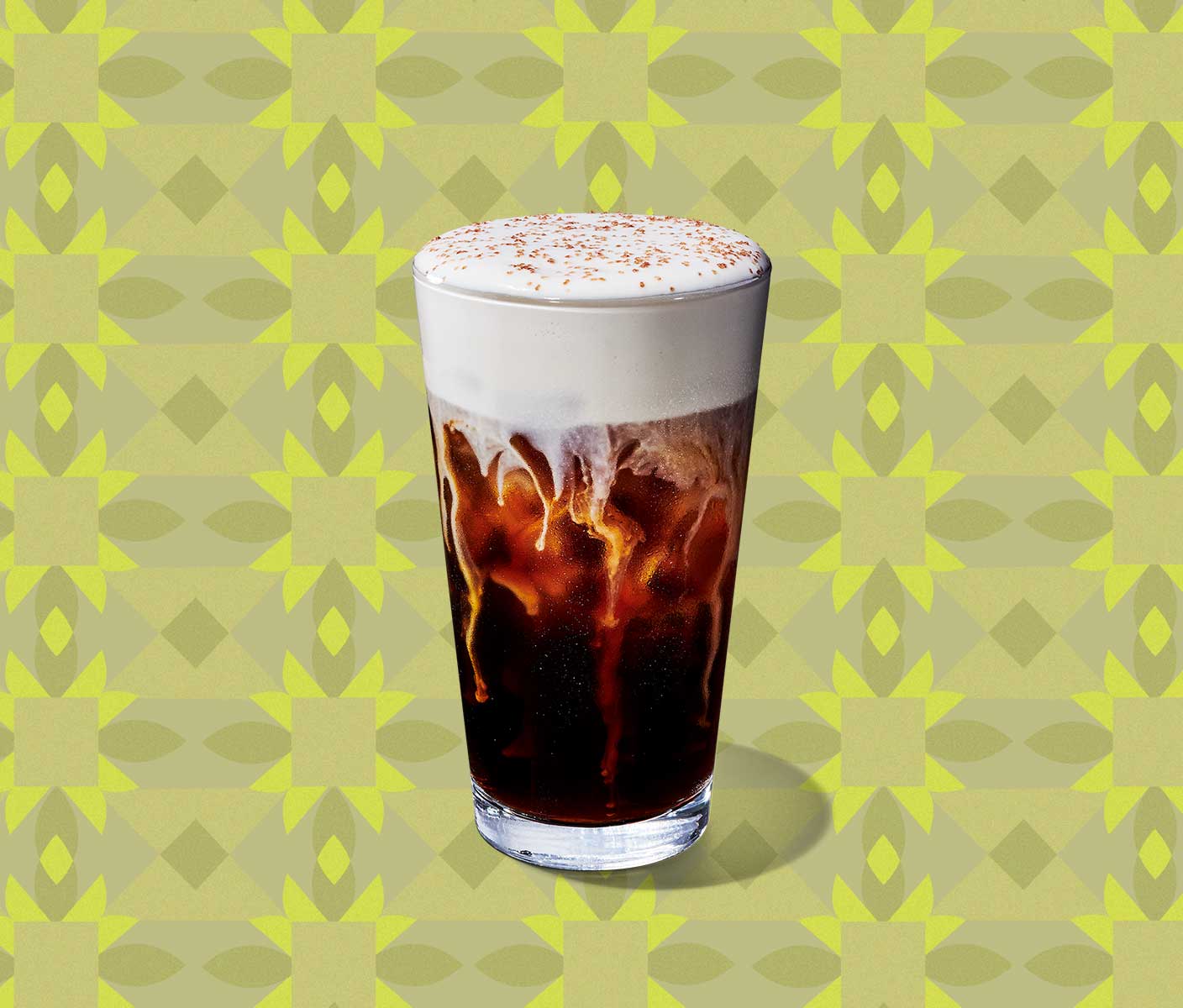 A cold coffee with thick, foamy topping in a tall, clear glass.