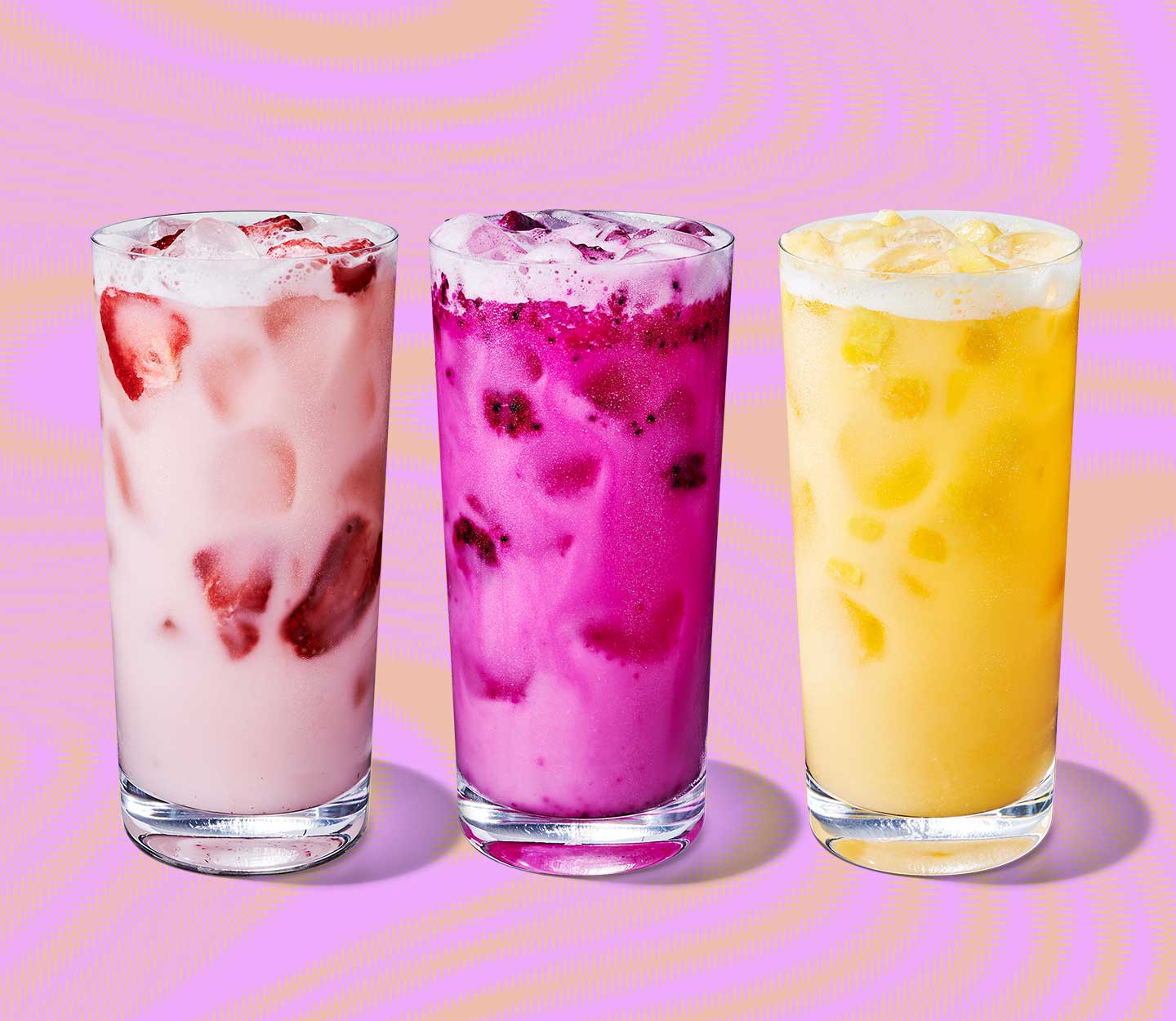 A trio of bright colored iced drinks with fruity pieces in clear glasses lined up side by side.